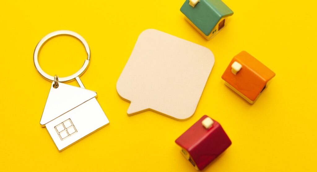 Brightly colored miniature houses and a house-shaped keychain against a yellow background, symbolizing content marketing in real estate.